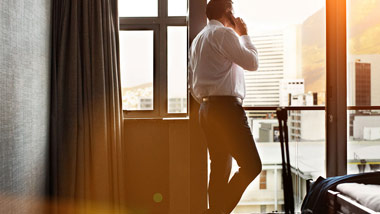 man on phone while looking out hotel room window
